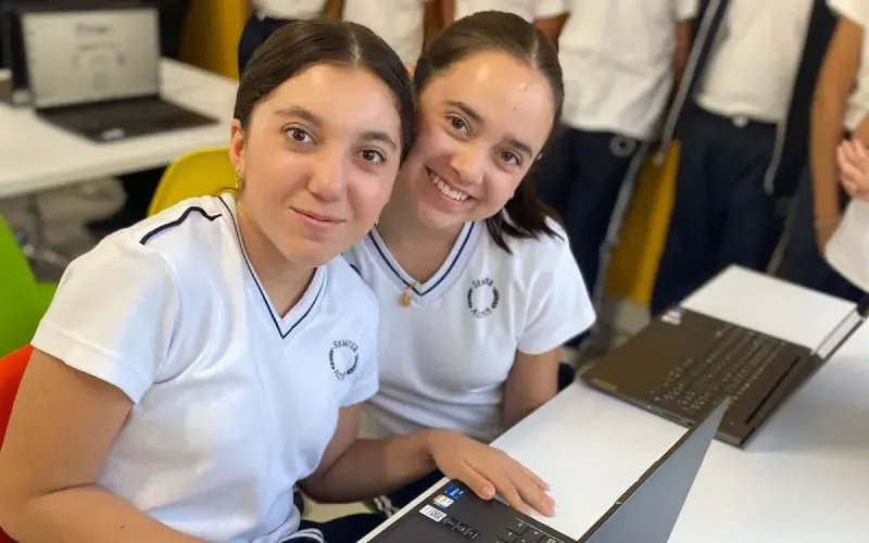 Dos estudiantes del Instituto Cumbres Tapachula trabajan juntas en computadoras durante una clase de tecnología en el aula.